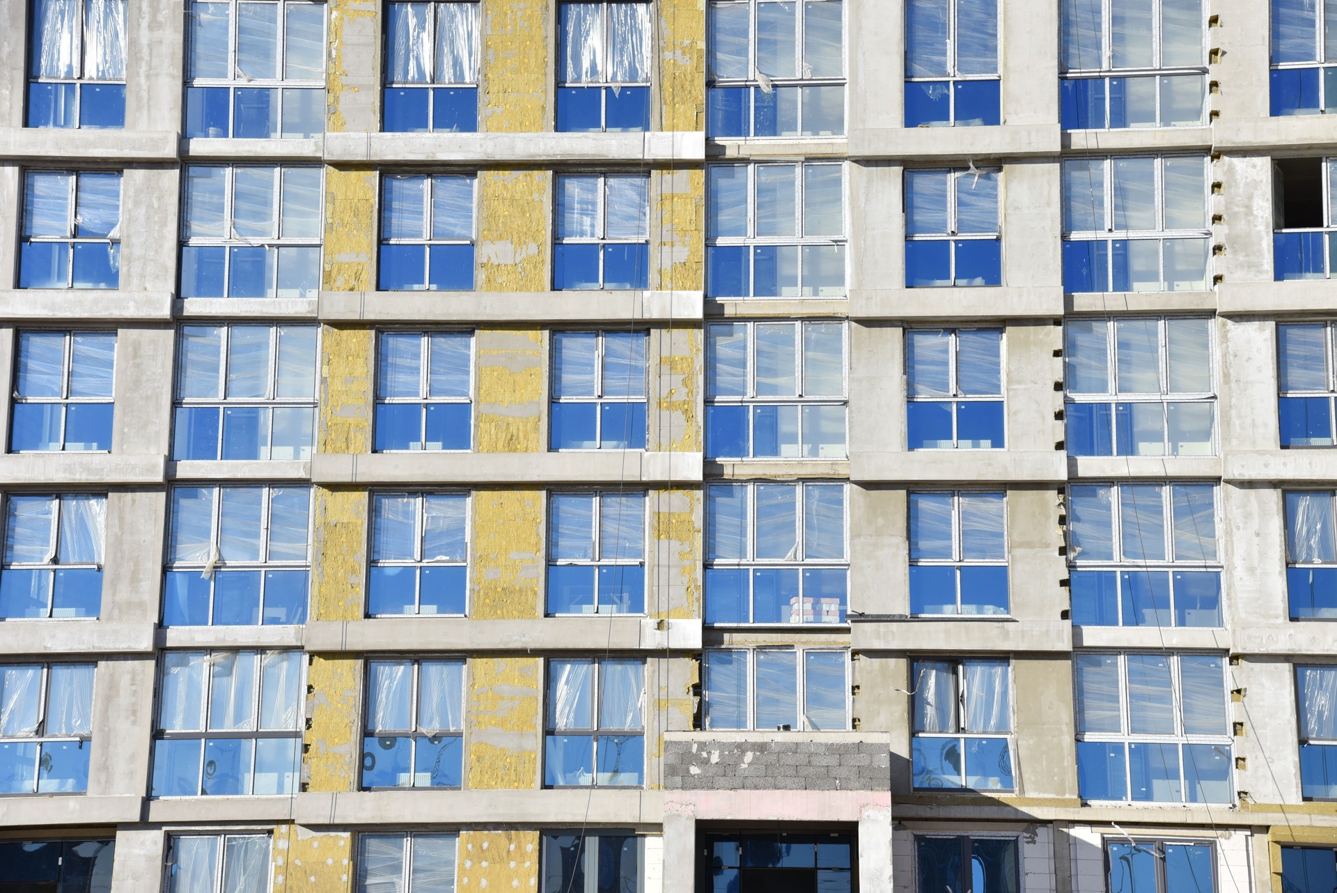 Laine minérale et plâtre appliqués sur la nouvelle façade de bâtiment à plusieurs étages. Isolation pour la protection thermique de la coque de la maison sur le chantier de construction. Programme de rénovation de logements, arrière-plan, texture